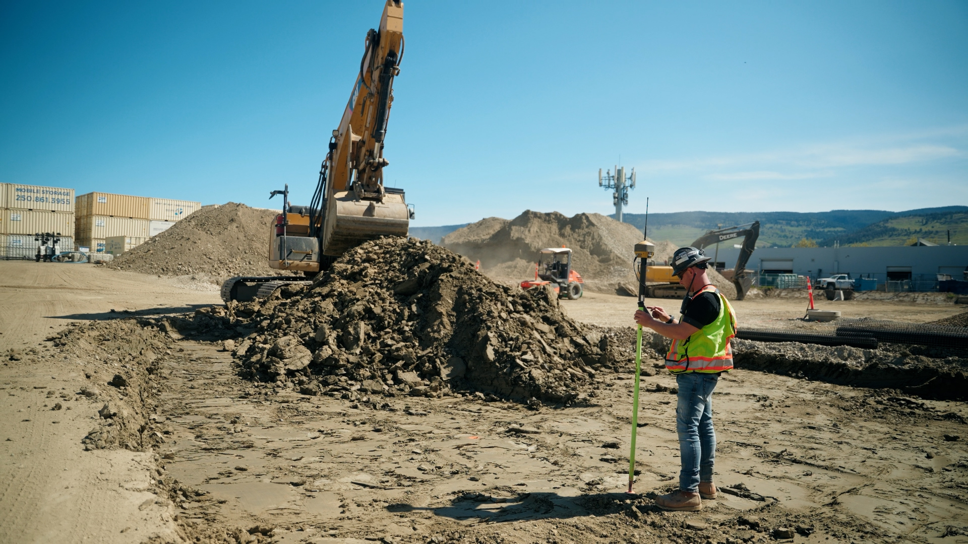 Dawson Civil surveying the new Dawson International Kelowna Dealership for underground utilities with an excavator in the background.